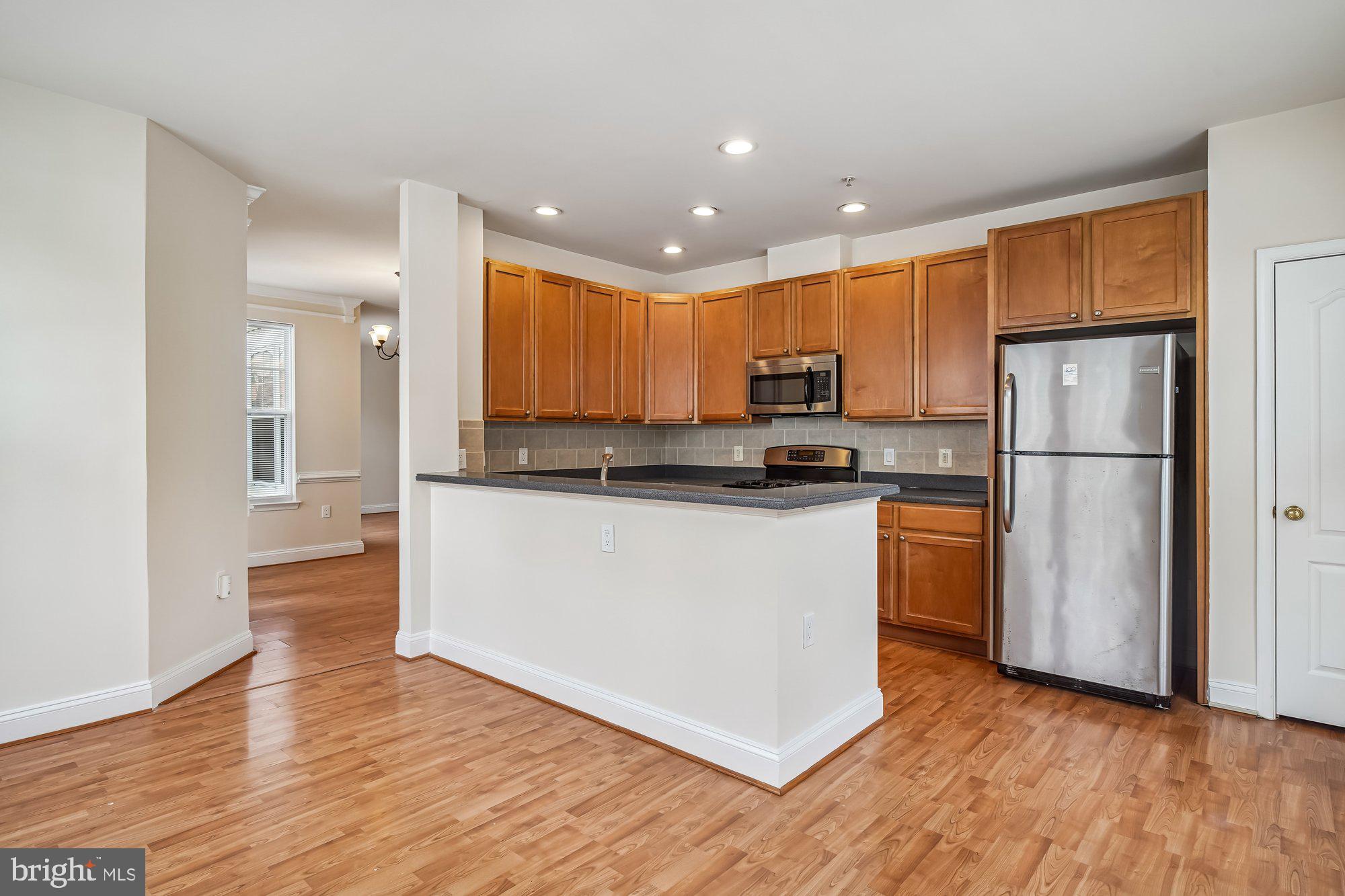 12824 Clarksburg Square Road, Unit 102 Clarksburg, MD 20871 - Photo 16 of 75 a kitchen with stainless steel appliances granite countertop a refrigerator sink and white cabinets