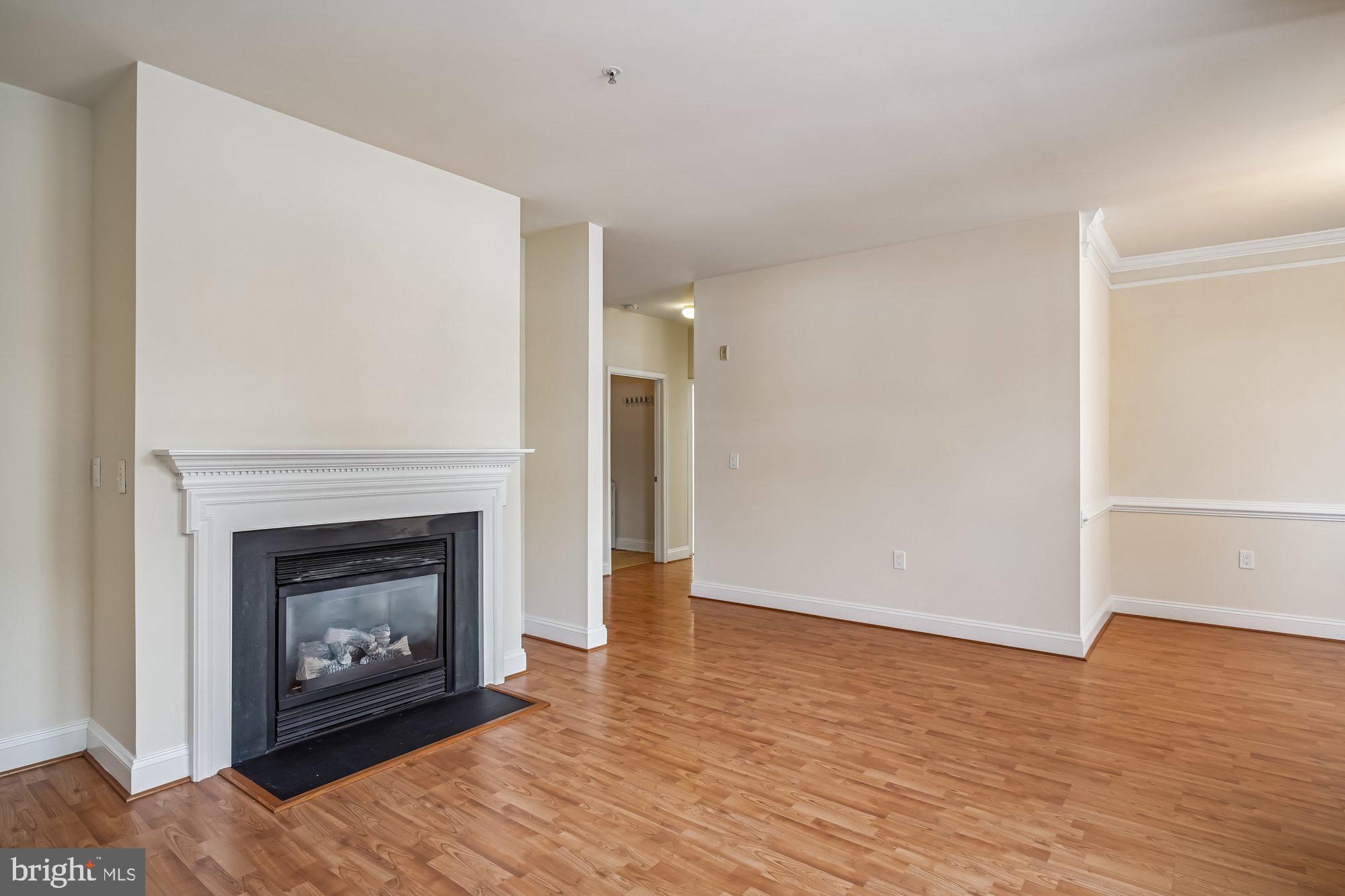 12824 Clarksburg Square Road, Unit 102 Clarksburg, MD 20871 - Photo 10 of 75 a view of an empty room with wooden floor fireplace and a window