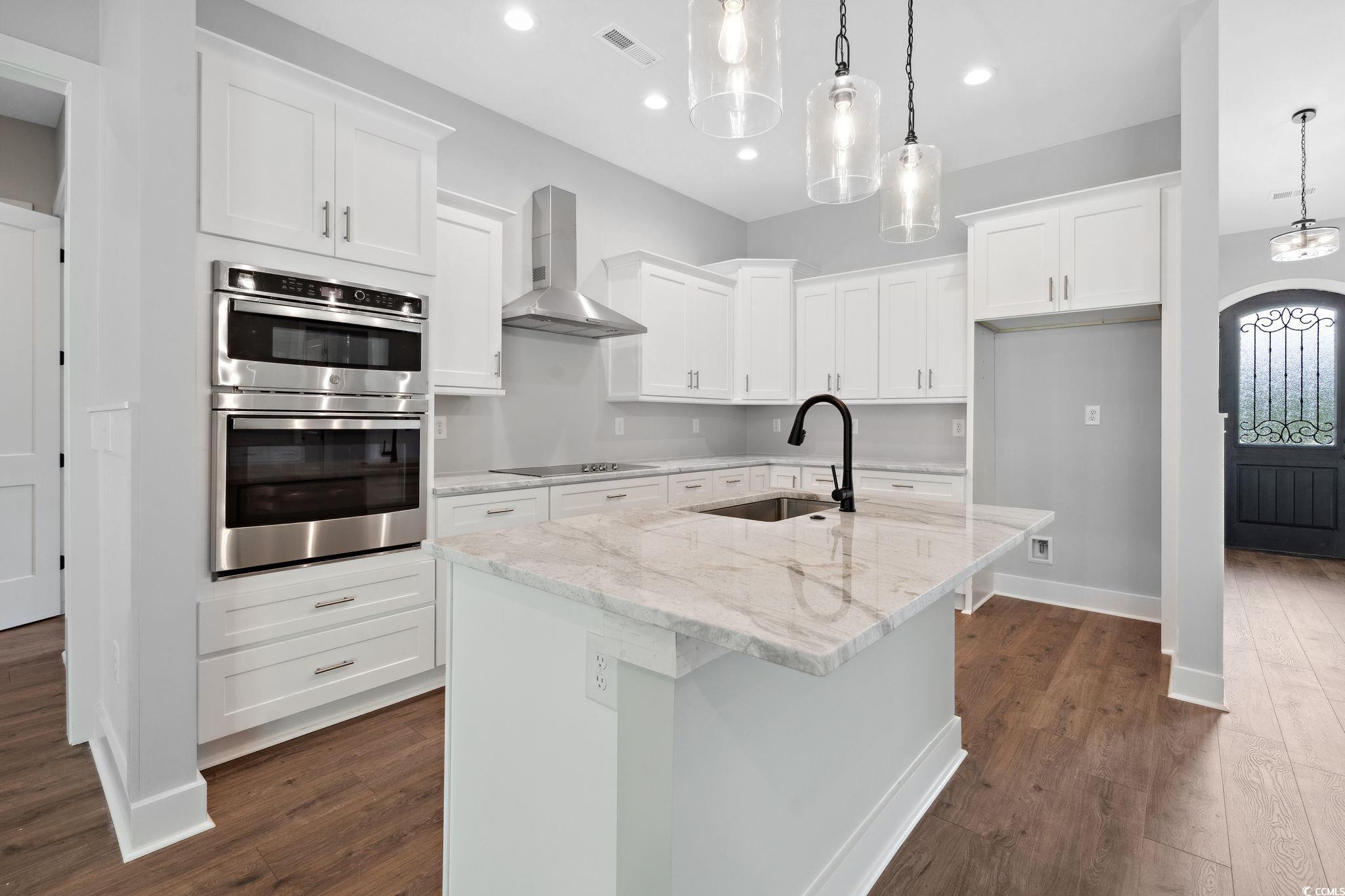 297 Waterfall Circle Little River, SC 29566 - Photo 11 of 40 Kitchen featuring wall chimney exhaust hood, stainless steel double oven, black electric stovetop, a sink, and dark wood finished floors