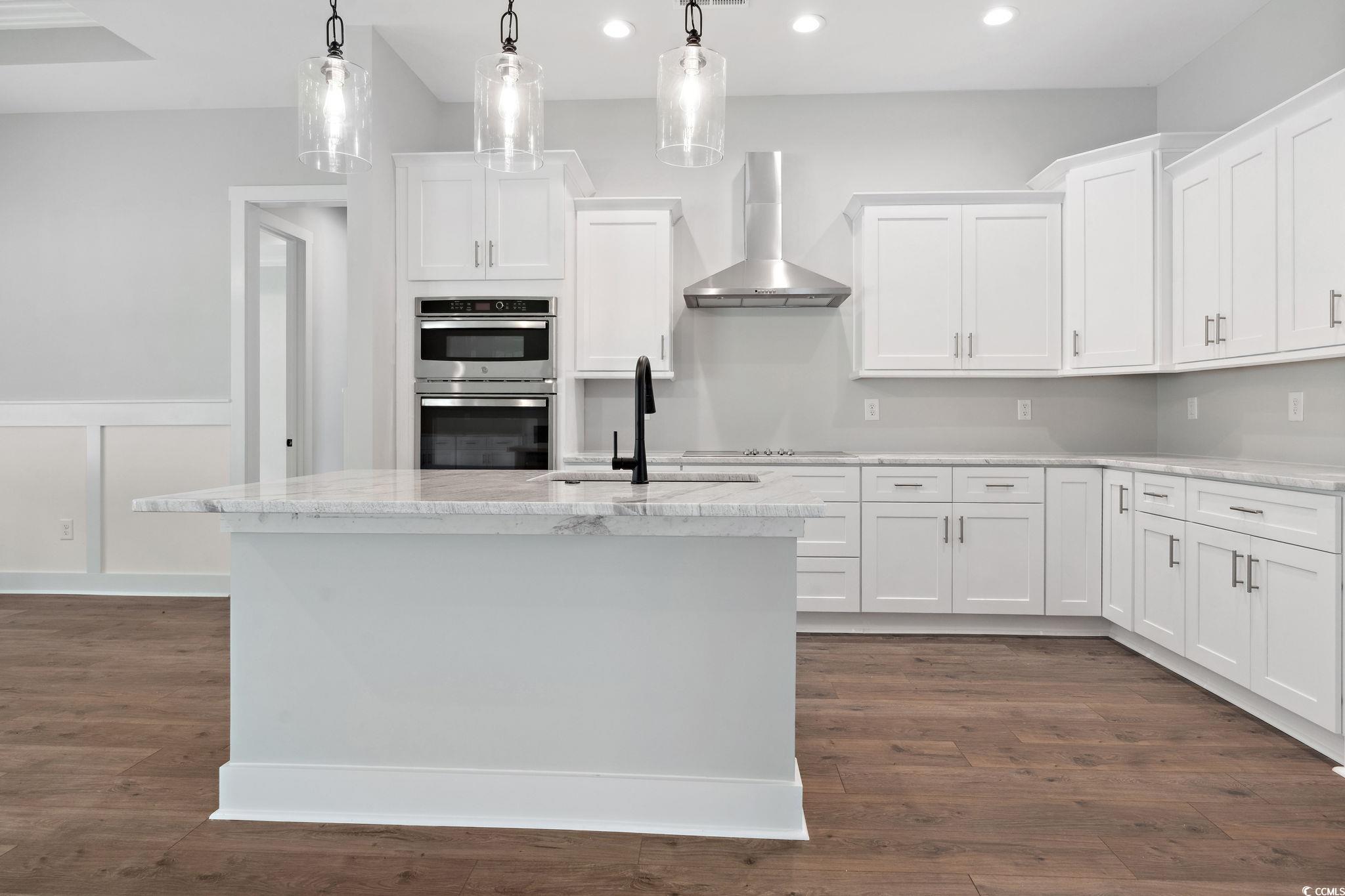 297 Waterfall Circle Little River, SC 29566 - Photo 12 of 40 Kitchen with wall chimney exhaust hood, recessed lighting, white cabinets, a sink, and double oven
