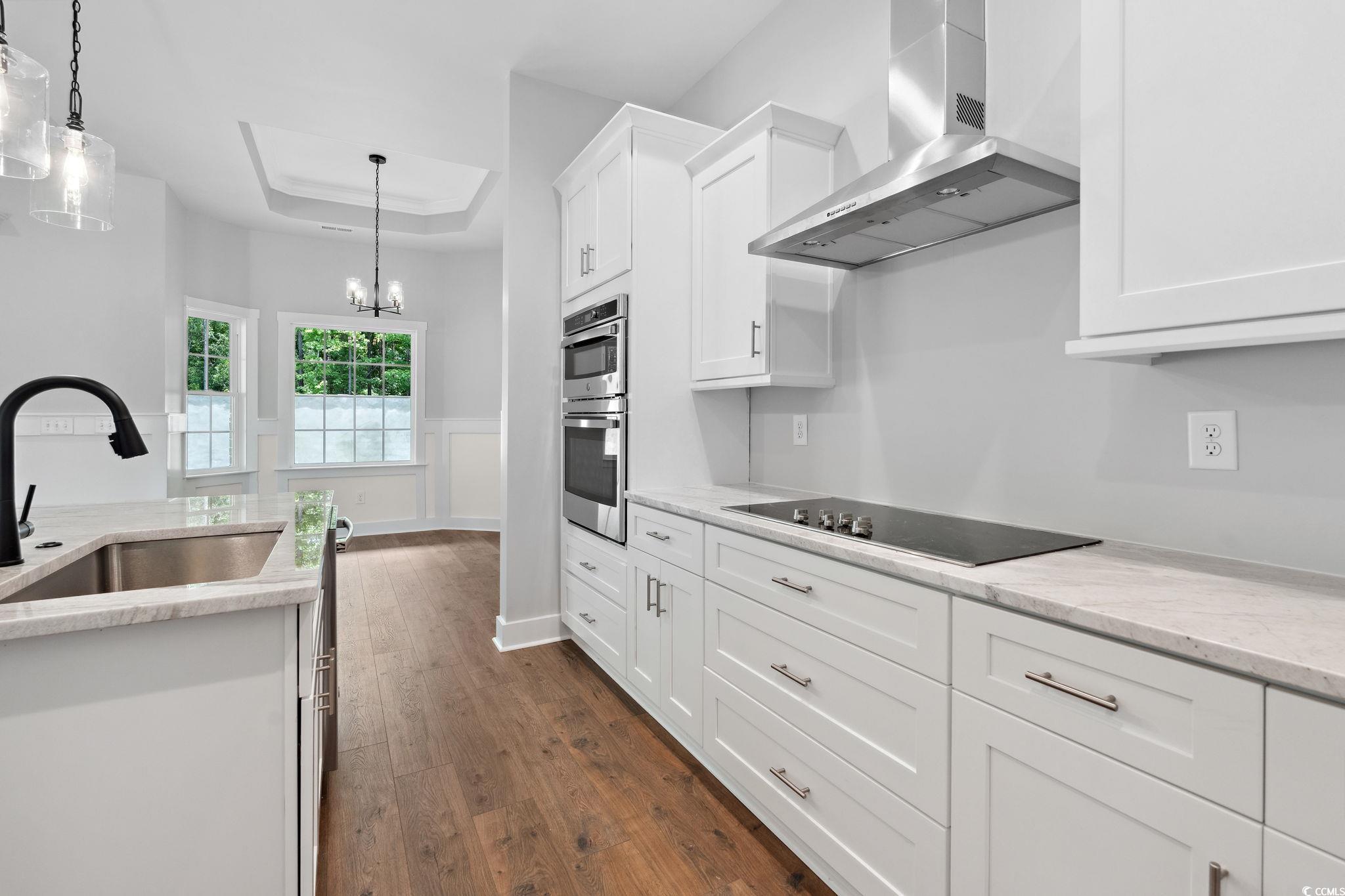 297 Waterfall Circle Little River, SC 29566 - Photo 13 of 40 Kitchen featuring wall chimney exhaust hood, a sink, black electric cooktop, dark wood finished floors, and white cabinetry