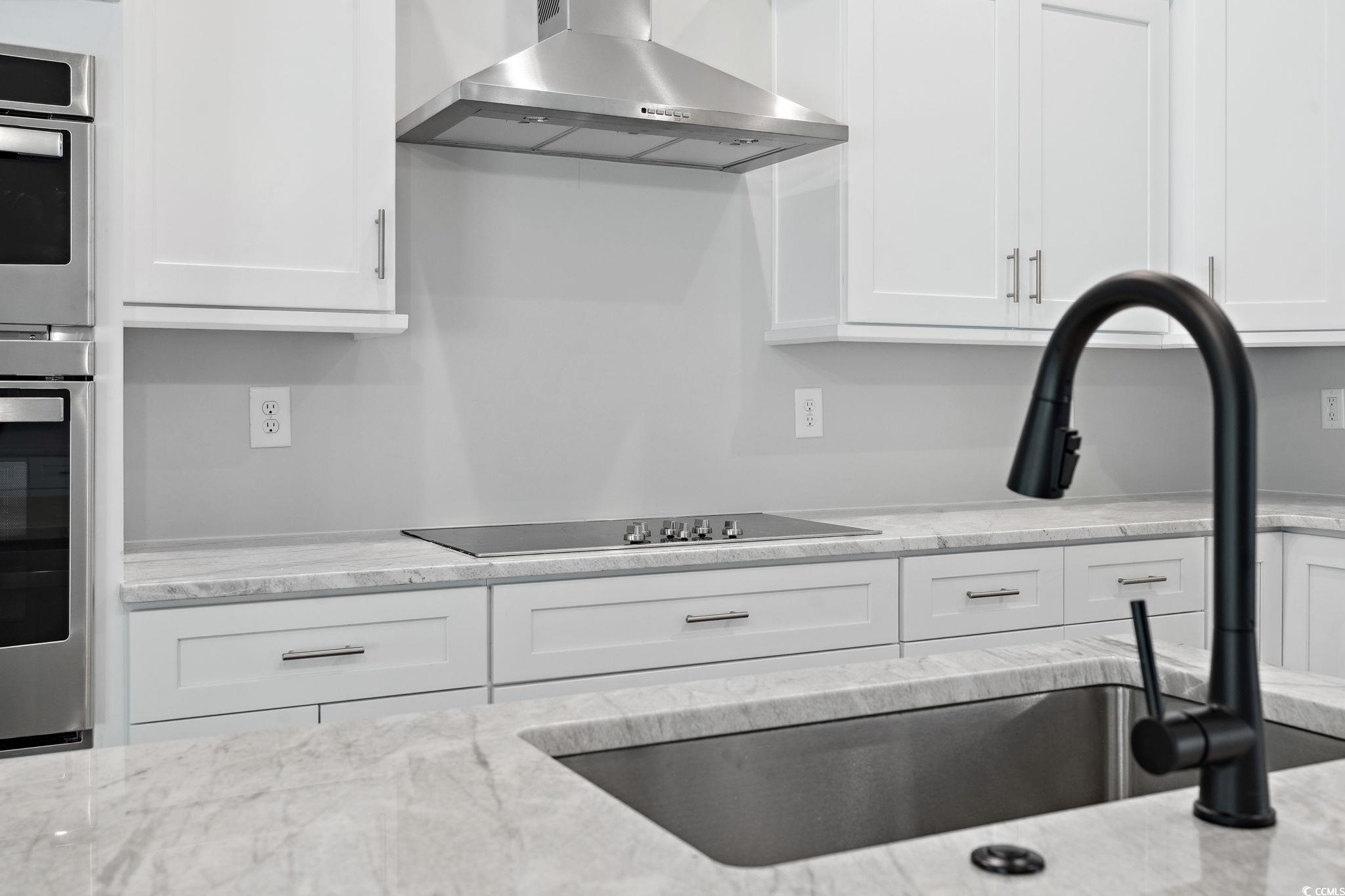297 Waterfall Circle Little River, SC 29566 - Photo 14 of 40 Kitchen featuring wall chimney range hood, stainless steel oven, white cabinetry, and black electric stovetop