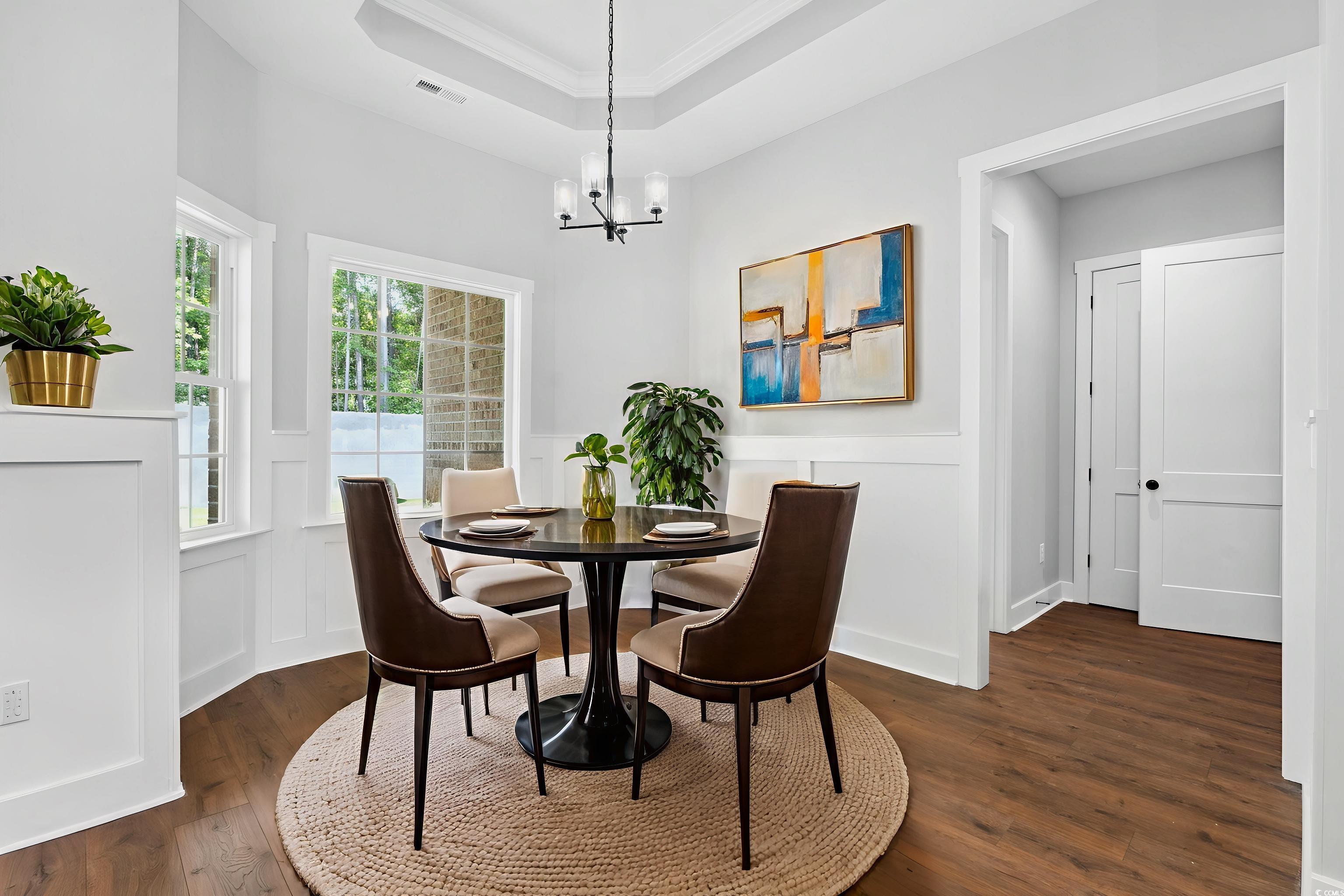 297 Waterfall Circle Little River, SC 29566 - Photo 19 of 40 Dining room featuring dark wood-type flooring, a raised ceiling, crown molding, a decorative wall, and a wainscoted wall