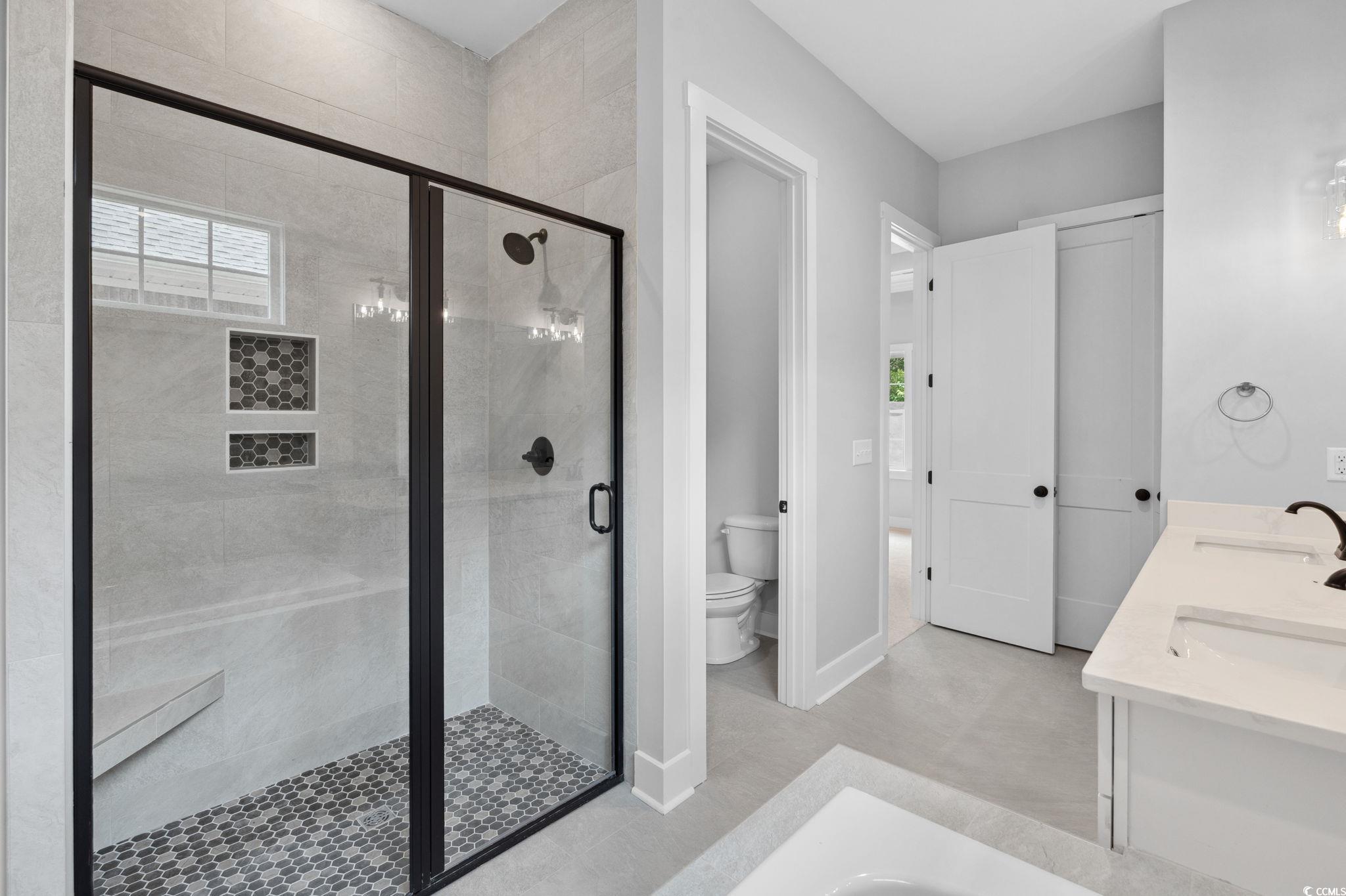 297 Waterfall Circle Little River, SC 29566 - Photo 23 of 40 Bathroom featuring a stall shower, toilet, double vanity, and baseboards