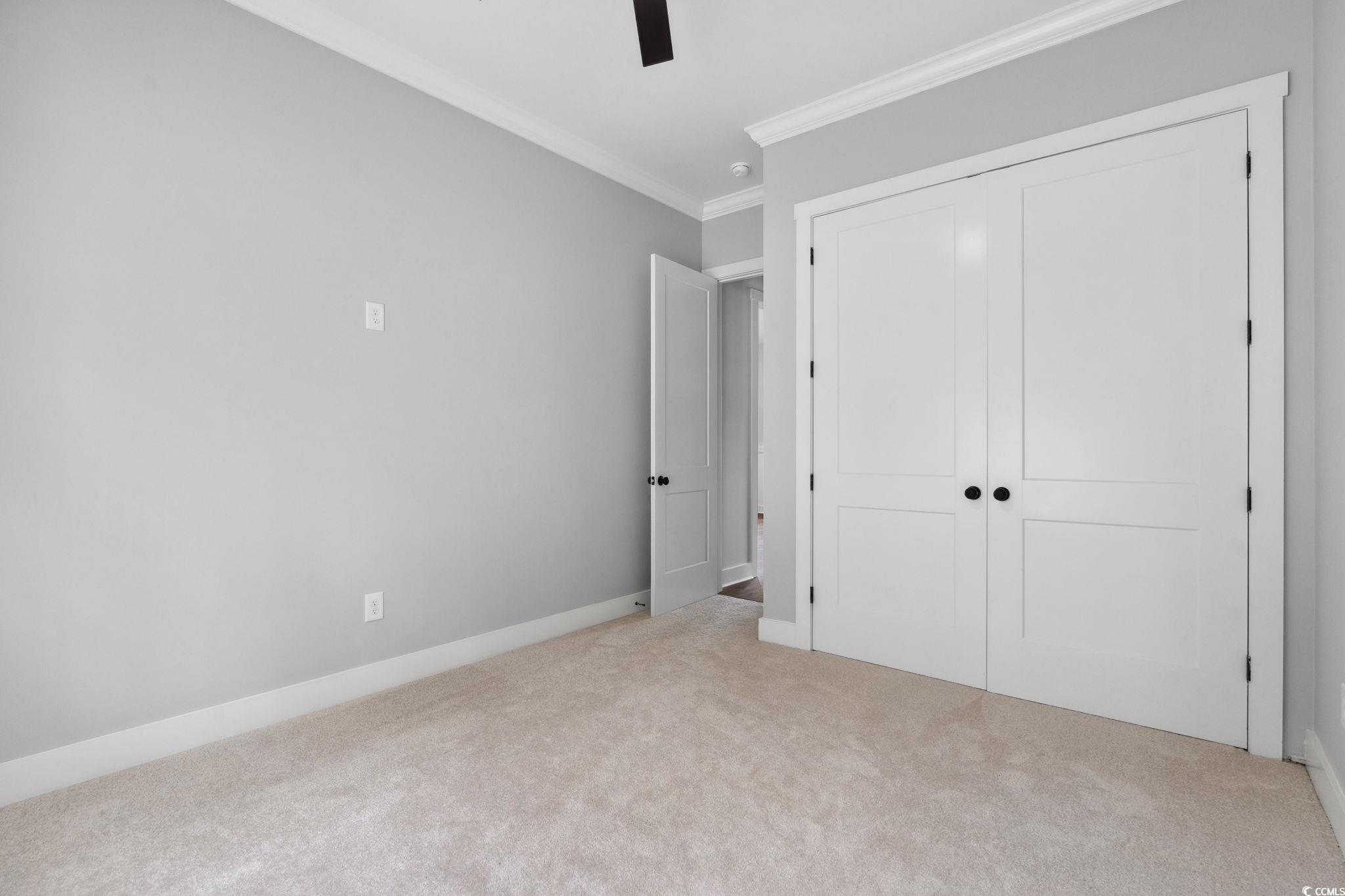 297 Waterfall Circle Little River, SC 29566 - Photo 30 of 40 Unfurnished bedroom with crown molding, carpet, a closet, ceiling fan, and baseboards