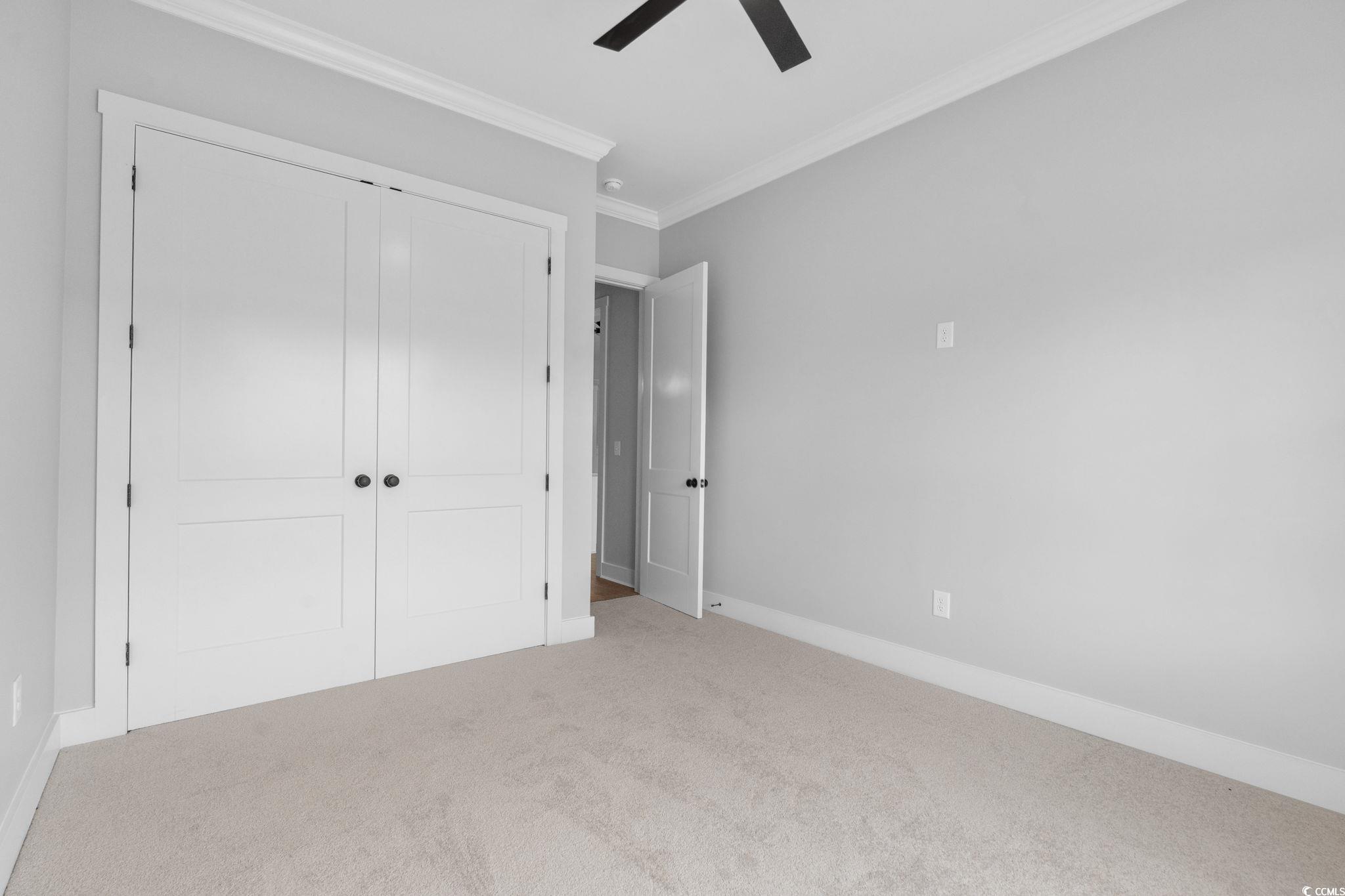 297 Waterfall Circle Little River, SC 29566 - Photo 33 of 40 Unfurnished bedroom with crown molding, carpet floors, a closet, baseboards, and a ceiling fan