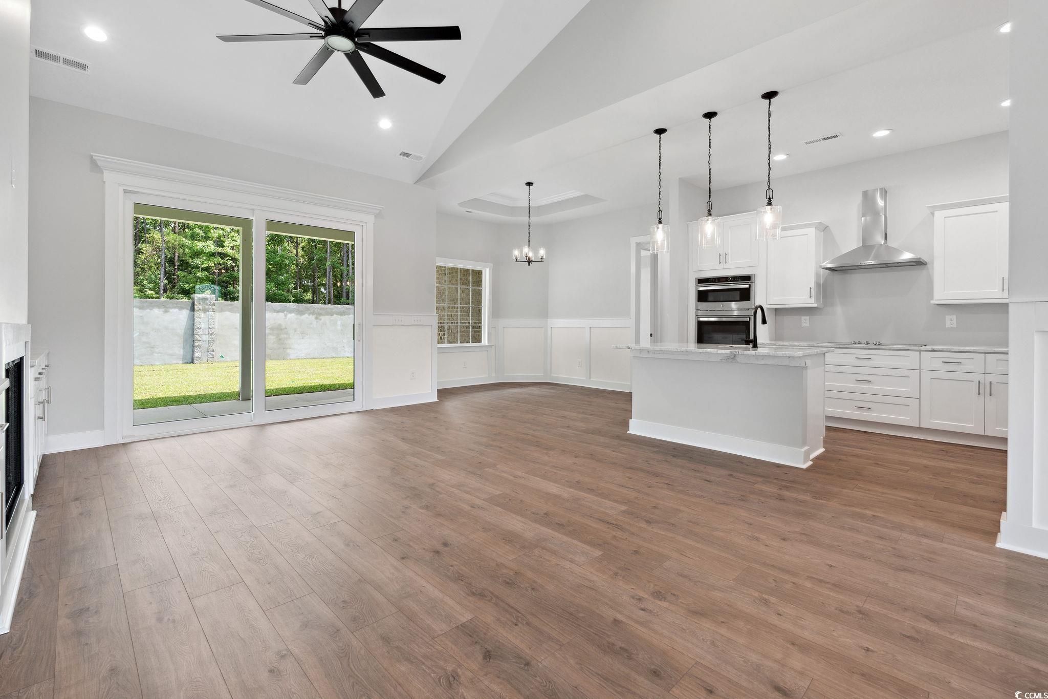 297 Waterfall Circle Little River, SC 29566 - Photo 10 of 40 Unfurnished living room with ceiling fan, wood finished floors, a wainscoted wall, a fireplace, and recessed lighting