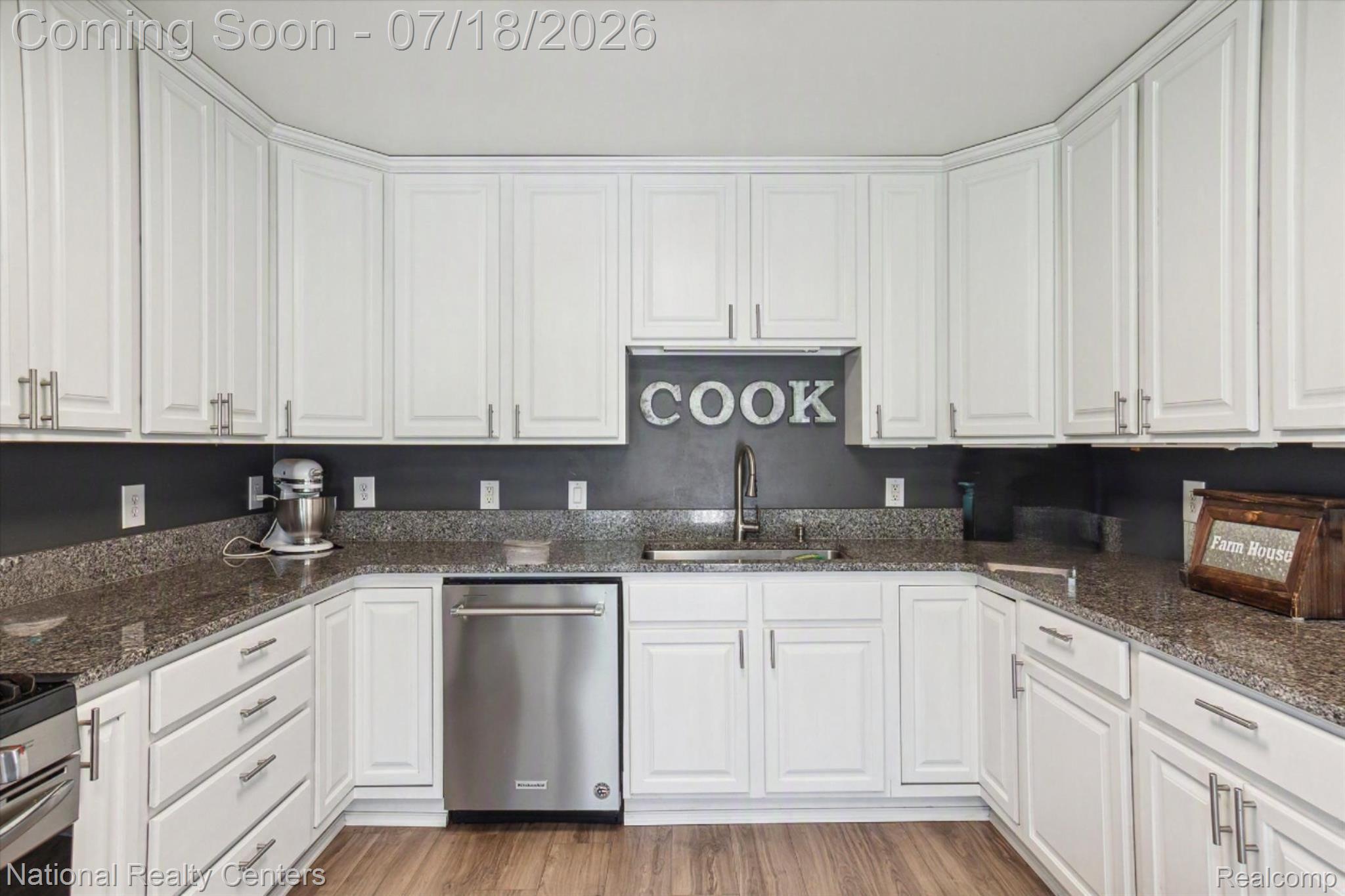 9589 Clinton Macon Road Tecumseh, MI 49286 - Photo 18 of 48 Kitchen featuring white shaker-style cabinetry with brushed nickel hardware, speckled countertops, a stainless steel dishwasher, and wood-finish flooring
