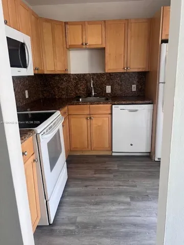 a kitchen with white cabinets a sink and white appliances
