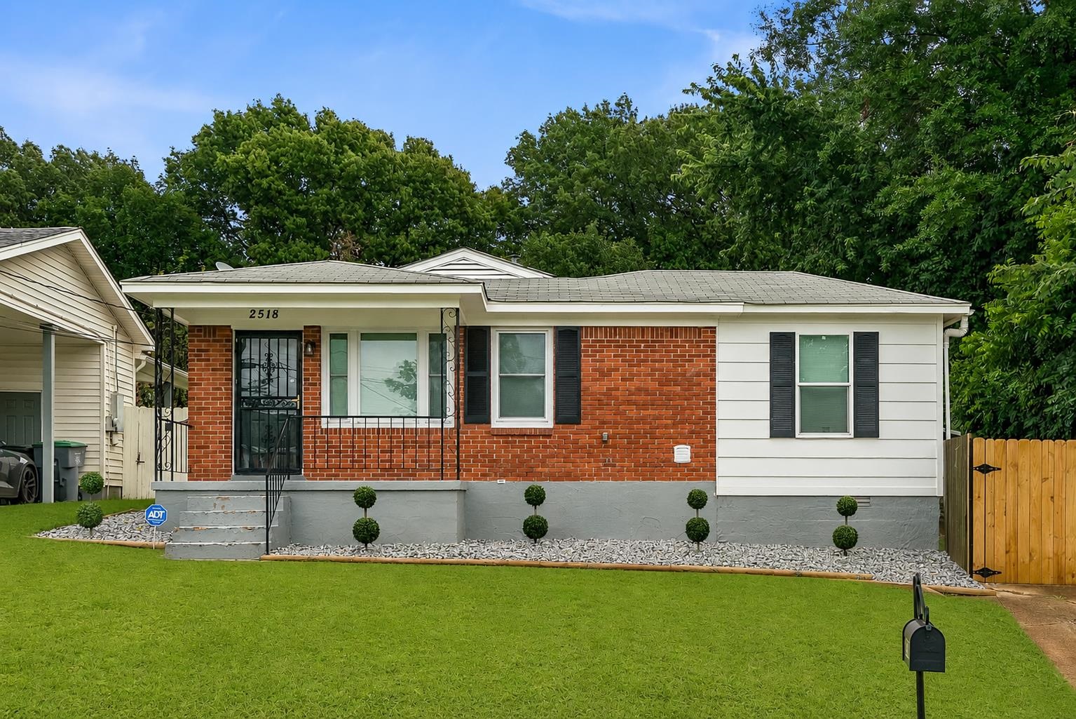 2518 Manchester Road Memphis, TN 38114 - Photo 1 of 23 Brick and siding exterior featuring a covered front entry with wrought iron railing, decorative window shutters, a front yard with manicured lawn, and a wood privacy fence