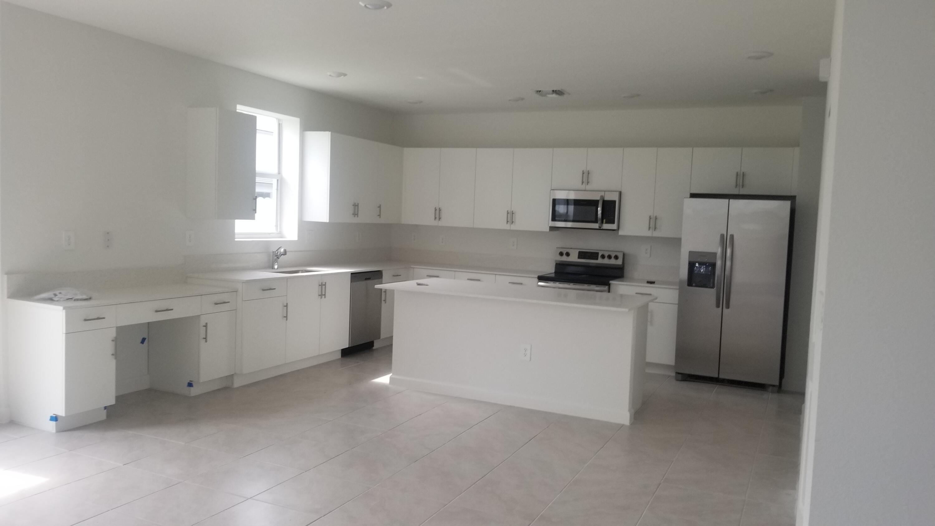 12736 Southwest 211th Street Miami, FL 33177 - Photo 4 of 18 a kitchen with white cabinets and white appliances