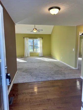 a view of an empty room with wooden floor and a window