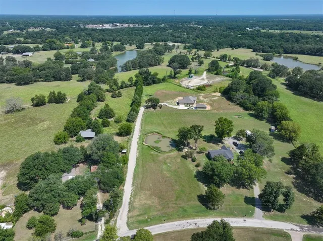 an aerial view of a residential houses with outdoor space and trees