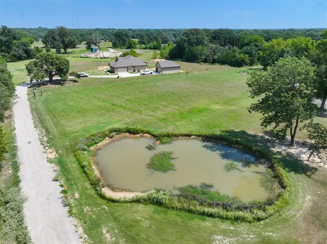 a view of a swimming pool with a yard and large trees