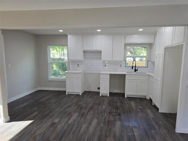 a kitchen with kitchen island wooden floors white walls appliances and cabinets