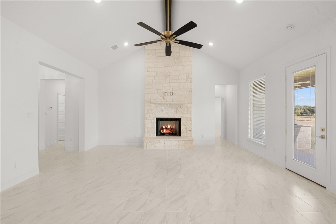 6512 Agave Court Bryan, TX 77808 - Photo 24 of 42 Unfurnished living room featuring high vaulted ceiling, a stone fireplace, ceiling fan, and beam ceiling