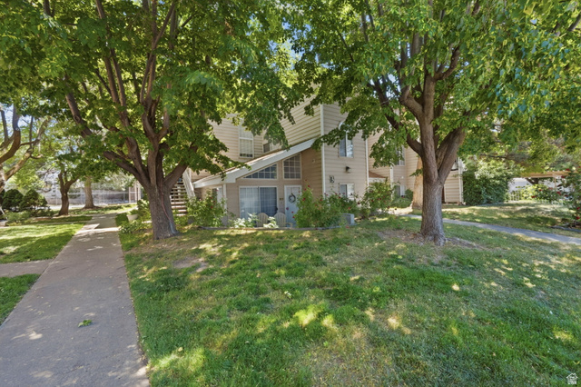 650 South Main Street, Unit 3304 Bountiful, UT 84010 - Photo 20 of 22 Two-story siding exterior featuring prominent gabled entryway, ground-level sliding glass door, mature shade trees, and a concrete pathway