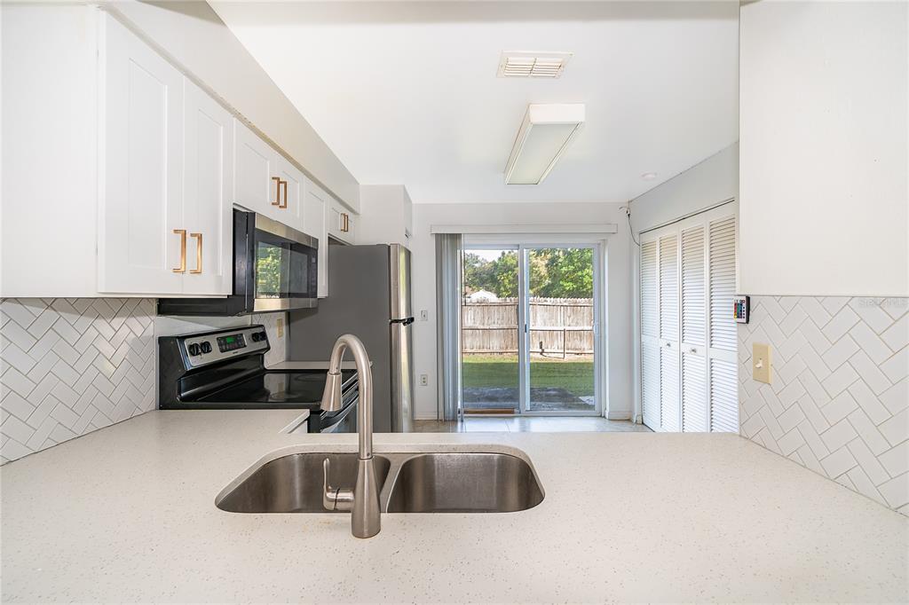 3135 Enclave Court Kissimmee, FL 34746 - Photo 5 of 22 a kitchen with stainless steel appliances granite countertop a sink a stove and a refrigerator with wooden floor