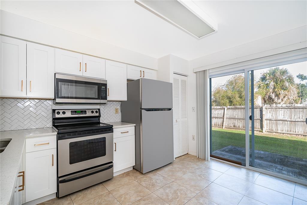 3135 Enclave Court Kissimmee, FL 34746 - Photo 6 of 22 a kitchen with granite countertop a refrigerator and a stove top oven