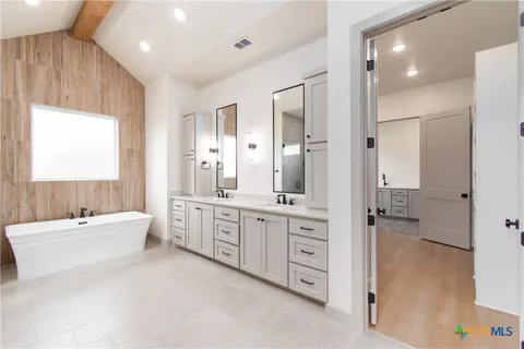 a large bathroom with a double vanity sink a mirror and a bathtub