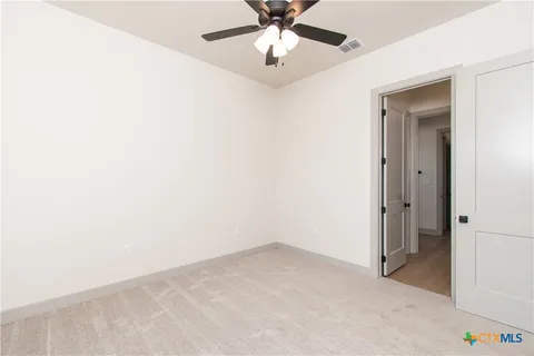 an empty room with closet and a chandelier fan