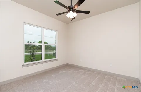 an empty room with a window and a fan