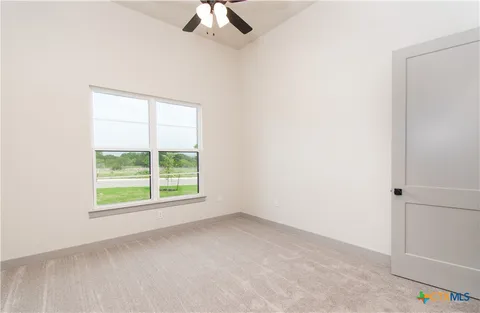 an empty room with a window and a ceiling fan