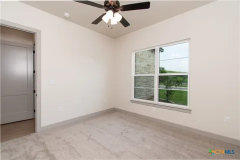 an empty room with windows and fan