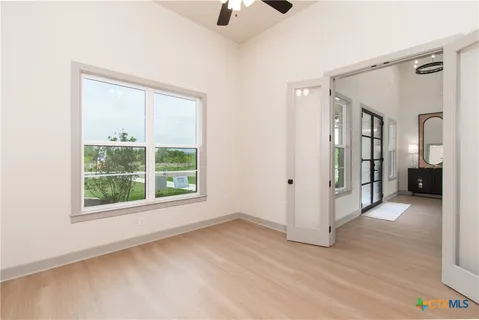 a view of an empty room with a window and wooden floor