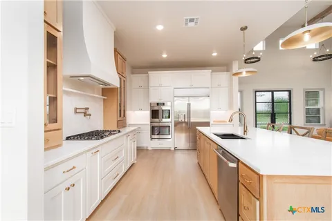 a large kitchen with stainless steel appliances kitchen island granite countertop a large counter top a stove and a sink