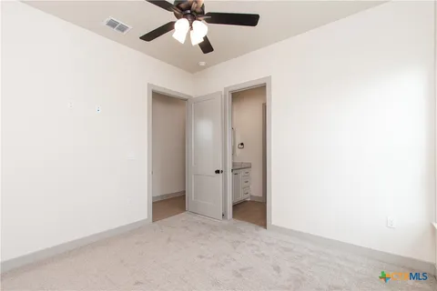 an empty room with closet and a chandelier fan