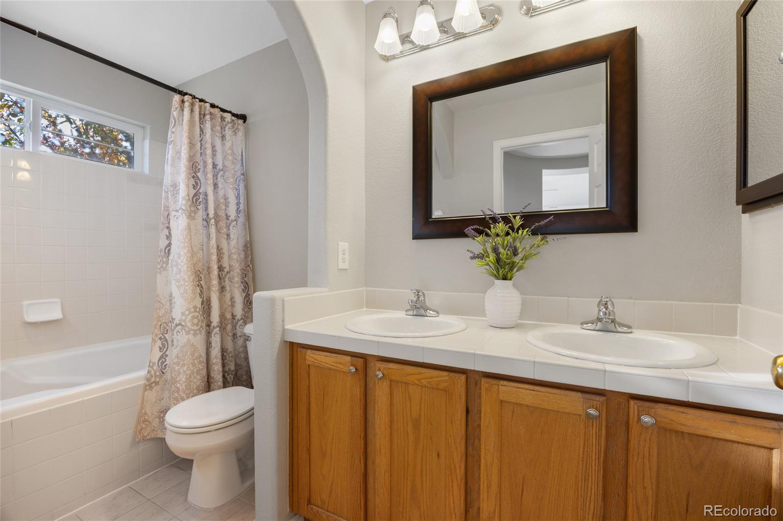 10655 Cherrybrook Circle Highlands Ranch, CO 80126 - Photo 18 of 42 a bathroom with a granite countertop sink toilet a mirror a bathtub and shower