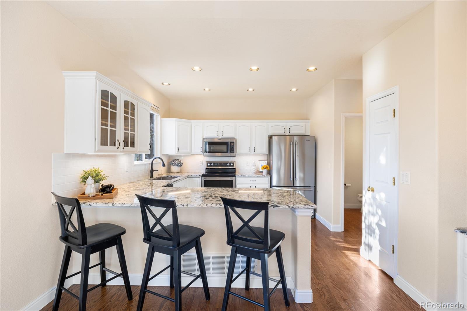 10655 Cherrybrook Circle Highlands Ranch, CO 80126 - Photo 7 of 42 a kitchen with stainless steel appliances kitchen island granite countertop a dining table chairs and white cabinets