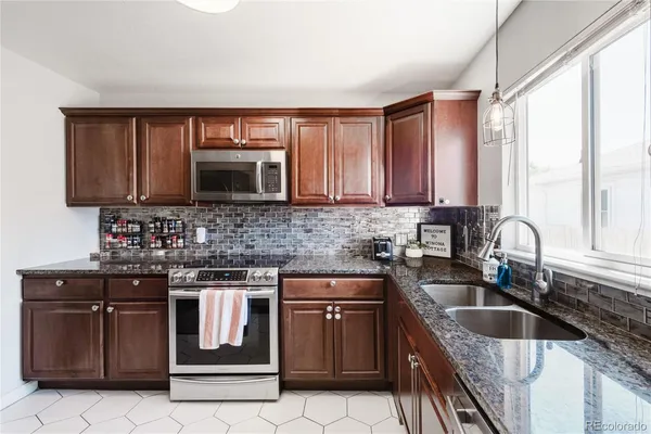 a kitchen with granite countertop a sink stove top oven and microwave