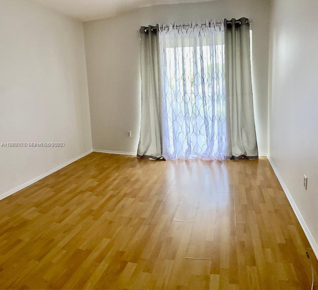 7725 Southwest 86th Street, Unit A1421 Miami, FL 33143 - Photo 2 of 6 a view of a room with wooden floor and a window