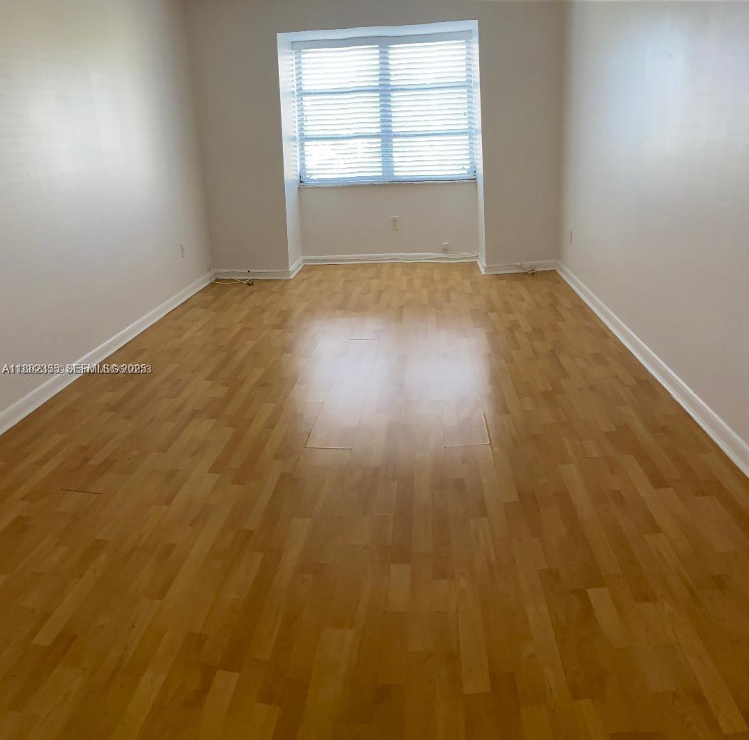 7725 Southwest 86th Street, Unit A1421 Miami, FL 33143 - Photo 3 of 6 an empty room with wooden floor and windows