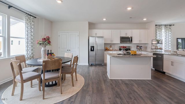 a kitchen with a dining table chairs and wooden floor