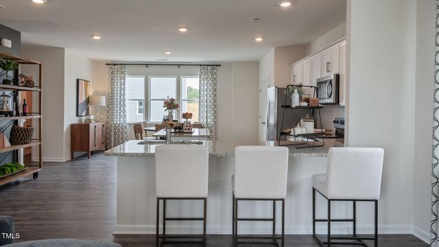 a kitchen with stainless steel appliances granite countertop a stove top oven a sink a dining table and chairs with wooden floor