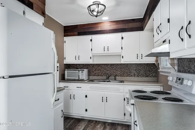 a kitchen with stainless steel appliances a refrigerator a sink and white cabinets
