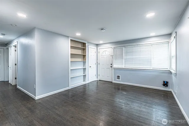 an empty room with cabinet and windows