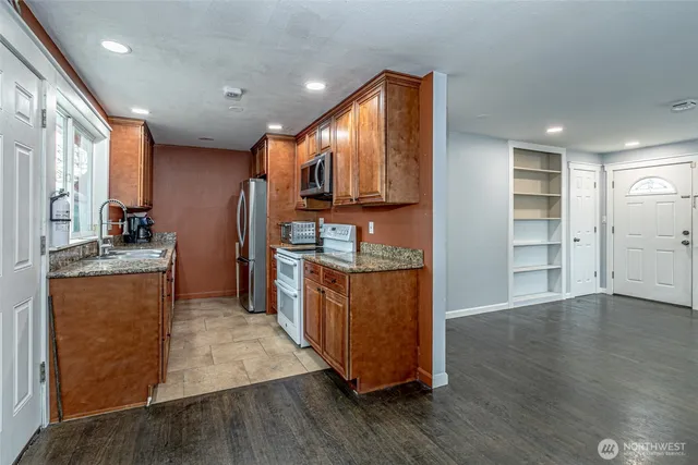 a kitchen with stainless steel appliances granite countertop a refrigerator a stove and a wooden floors