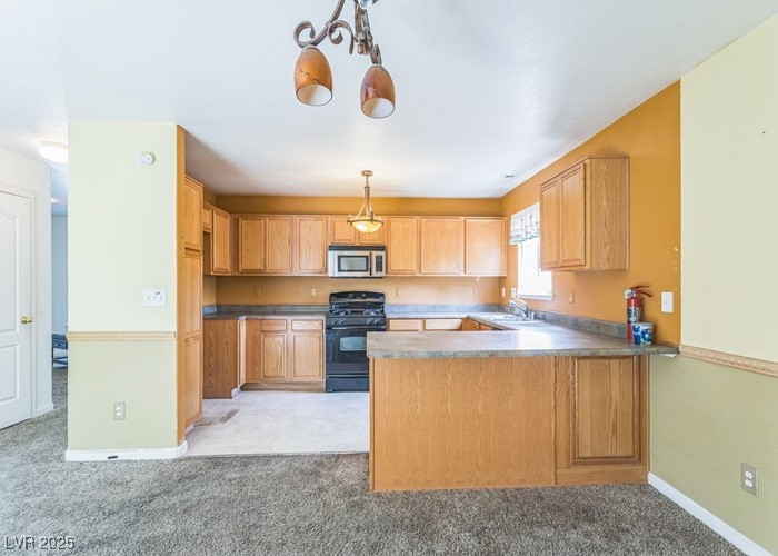 17710 Fairfax Court Reno, NV 89508 - Photo 8 of 19 Kitchen with a peninsula, black range with gas cooktop, stainless steel microwave, pendant lighting, and light colored carpet