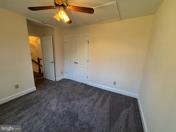 an empty room with closet and a chandelier fan