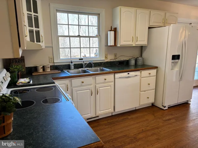 a kitchen with granite countertop white cabinets and white appliances