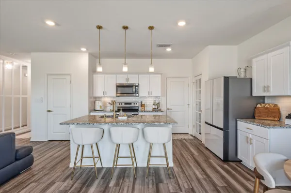 a kitchen with stainless steel appliances a dining table chairs refrigerator and microwave