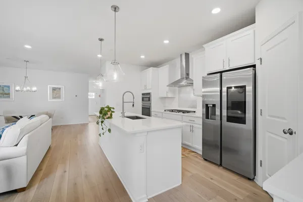 a large kitchen with stainless steel appliances kitchen island a large counter top and wooden floors