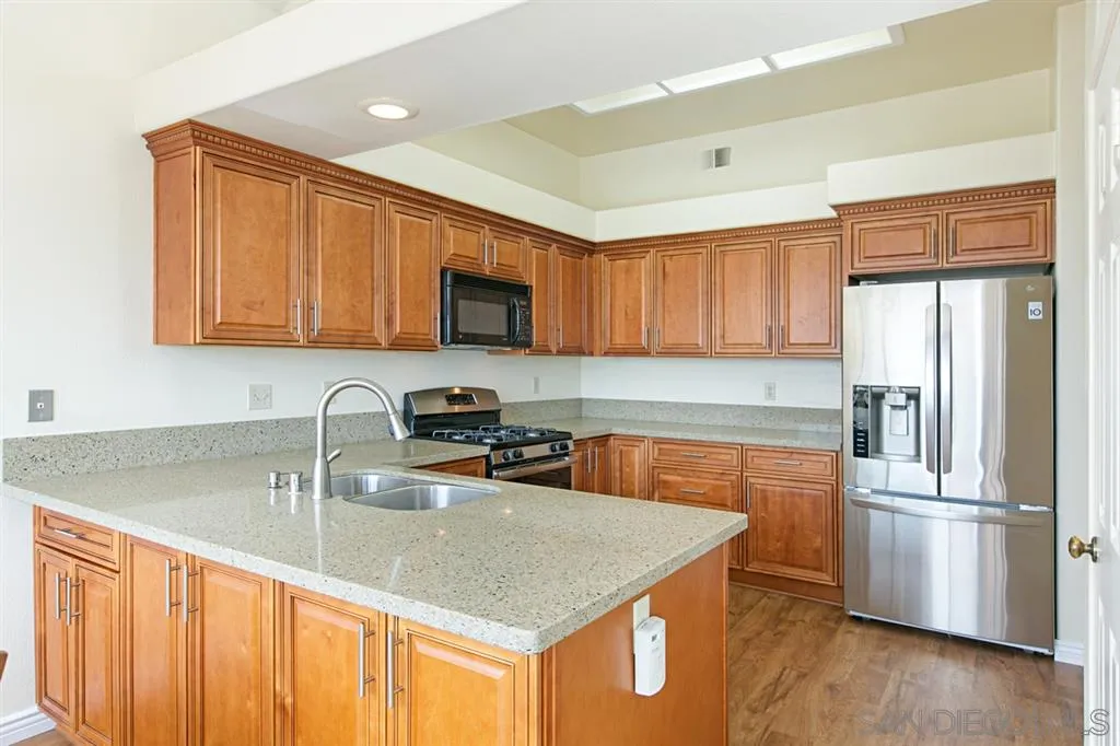 5064 Frazee Road Oceanside, CA 92057 - Photo 3 of 25 a kitchen with stainless steel appliances granite countertop a sink stove refrigerator and cabinets