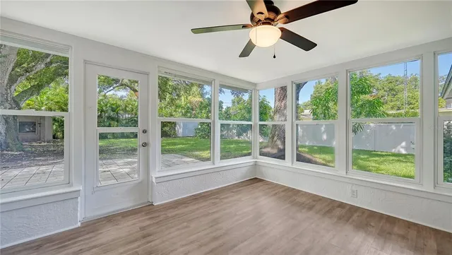 a view of an empty room with wooden floor and a large window