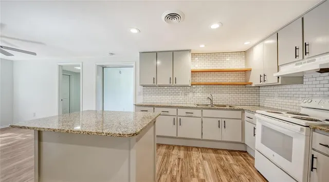 a kitchen with stainless steel appliances granite countertop a sink stove and cabinets