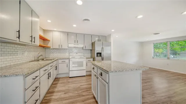 a kitchen with granite countertop sink stainless steel appliances and white cabinets